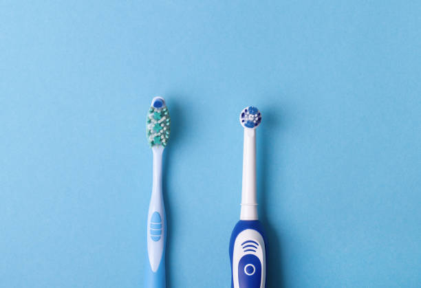electric and classic toothbrush on a blue background stock photo