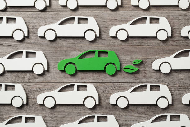 Electric car among others gasoline vehicles Top view of green electric car with leaves symbol between polluting fossil combustion vehicles. Wooden cut out of single pollution free electric car in the middle of others. Eco friendly, clear ecology driving, no pollution and emmission free transition concept. hybrid vehicle stock pictures, royalty-free photos & images