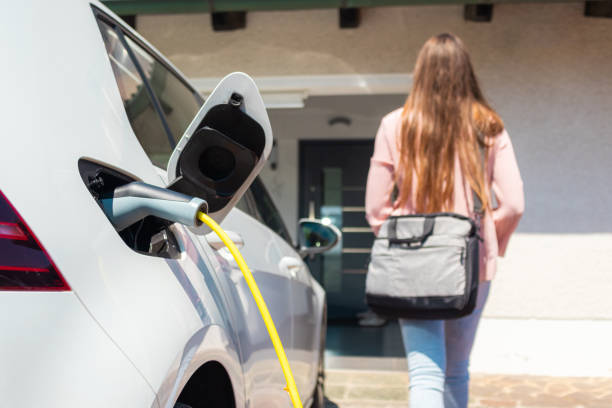 electric car charger plugged in - electric car woman bildbanksfoton och bilder