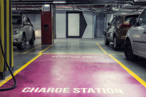 Electric car charging station in underground indoor parking of mall or office building. Reserved parking lot for environment friendly green energy zero emiision vehicles with fast charger plugs stock photo