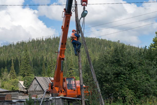 electric climbed onto the wood transmission pole structure and fix to  it with chains to the crane boom for dismantlement of an installation. - kemerovo imagens e fotografias de stock