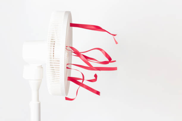 Electric fan with red ribbons on white background close-up, side view. stock photo