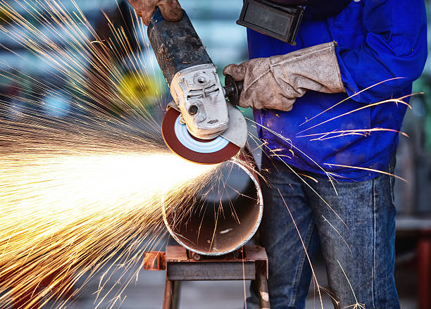 Electric wheel grinding on steel pipe in factory stock photo