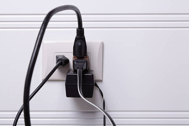Electrical Danger Several electric cables plugged into an electrical outlet. plug adapter stock pictures, royalty-free photos & images
