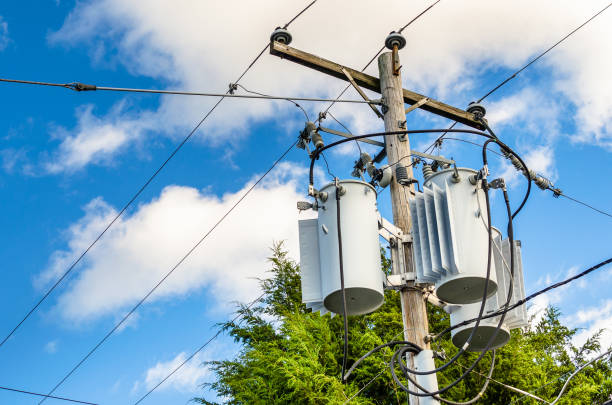 Electricity Pole with Transformers and Blue Sky Photo of Electricity Distribution Pole with Transformers aginst Bleu Sky with Clouds electricity transformer stock pictures, royalty-free photos & images