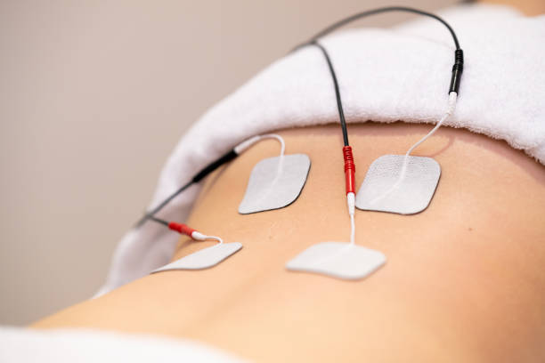 Electro stimulation in physical therapy to a young woman Electro stimulation in the lumbar zone in physical therapy to a young woman in a physiotherapy center. electrode stock pictures, royalty-free photos & images