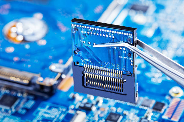 Electronic technician holding tweezers with microchip and assemblin a circuit board. Production computer or repair pc system. stock photo