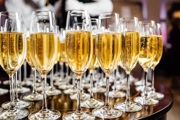Elegant glasses with champagne standing in a row on serving table during party or celebration stock photo