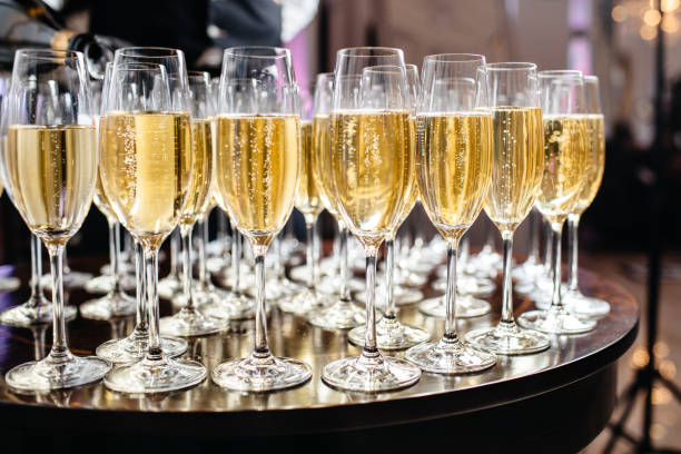 Elegant glasses with champagne standing in a row on serving table during party or celebration stock photo