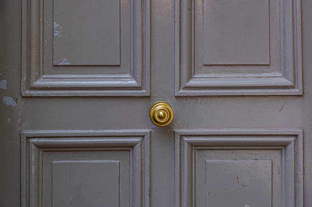 Elegant gray color painted wooden door surface with relief frames and round vintage knob in center. Details of Paris door of old building in France. Simplicity of classic architecture. stock photo