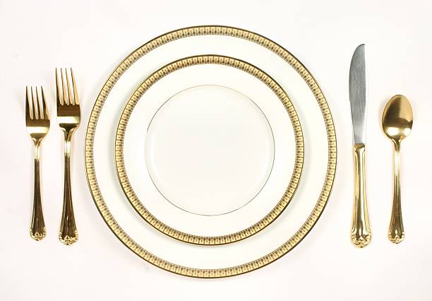 Elegant Table Setting with white and gold plates and silverware stock photo