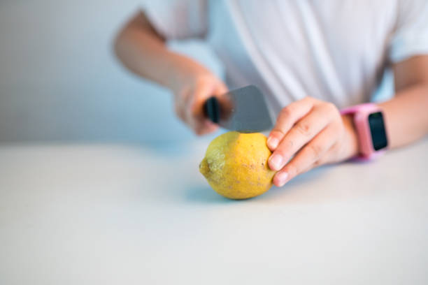 elementary asian female cutting lemon on table  Portable DVD Player stock pictures, royalty-free photos & images