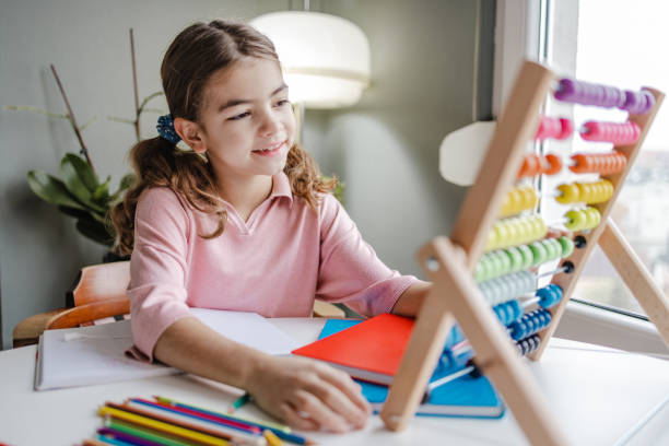 Elementary school female uses abacus at home stock photo