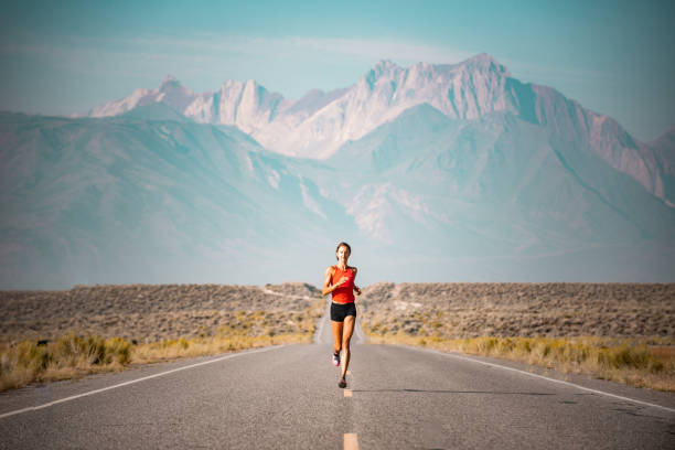 Elite Women Athlete Running Up A Road in the Sierra Mountains, California stock photo