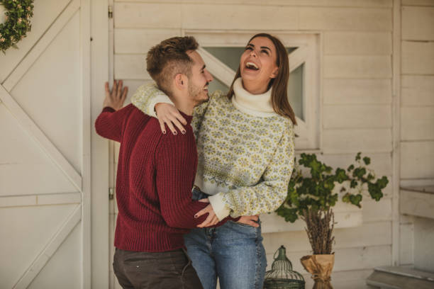 Embraced cheerful couple dancing outside front door of a rustic cabin stock photo