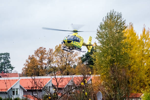 Emergency ambulance rescue helicopter landing in bad weather in a residential area with buildings and trees. stock photo