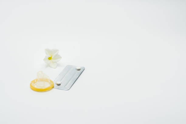 les pilules contraceptives d’urgence, de condom et de fleurs sur fond blanc - pilule du lendemain photos et images de collection