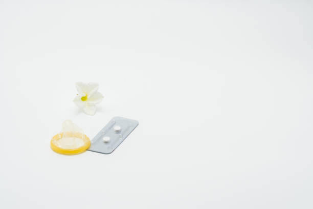 pilules contraceptives d’urgence avec préservatif et fleurs sur fond blanc - pilule du lendemain photos et images de collection