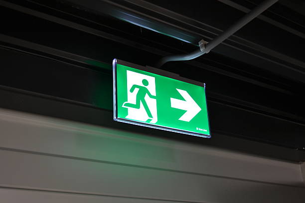 Emergency Exit Sign Light An emergency exit light telling staff where to go in case of an emergency and how to leave the building in case of fire flash stock pictures, royalty-free photos & images