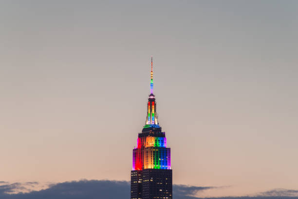 Empire State Building pride colors A close-up of the Empire State Building displaying Pride colors taken from Brooklyn just after sunset. nyc pride parade stock pictures, royalty-free photos & images