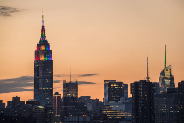 Empire State Building pride sunset A partial skyline of Midtown Manhattan with the Empire State Building displaying Pride colors taken from Brooklyn just before at sunset. nyc pride parade stock pictures, royalty-free photos & images