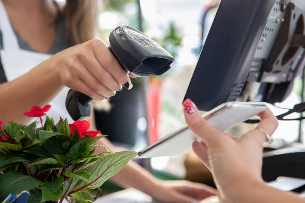 Employee scans smart phone to take payment at garden center or plant nursery stock photo