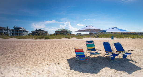 Empty Beach Chairs Beach chairs and umbrellas sit unattended on a clean, sandy beach. north carolina beach stock pictures, royalty-free photos & images