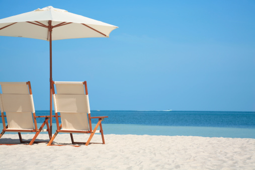 pair of white empty chairs and a white umbrella at a beach in Florida, USA