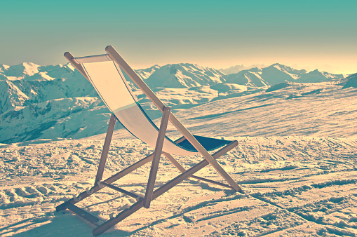 Empty deckchair on the side of a ski slope, vintage process