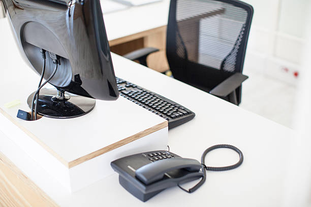 Empty desk with telephone, keyboard, computer and chair. stock photo