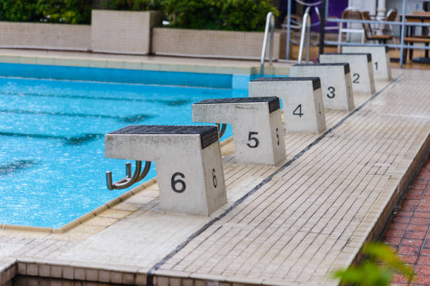 empty diving block stands with numbers in outdoor swimming pool on rainy day empty diving block stands with numbers in outdoor swimming pool on rainy day asien startblock stock pictures, royalty-free photos & images