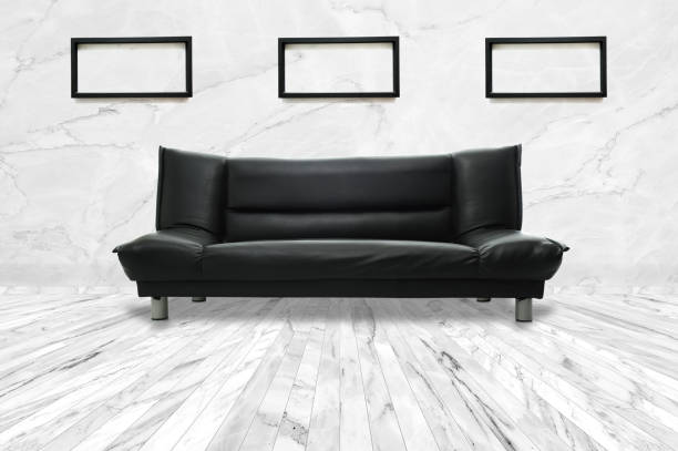 Empty modern living room with black leather sofa on marble floor and three black frames on marble wall. for Interiors design (High resolution). stock photo
