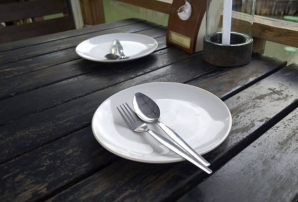 Empty plate with spoon and fork on wooden table stock photo