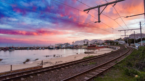 Empty Railway line next to a harbour at the ocean with a spectacular sunset Kalk Bay Harbour Cape Town stock photo