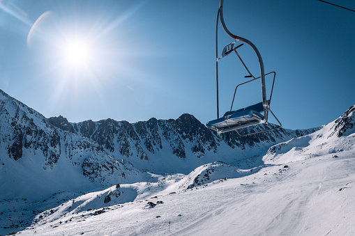Empty skilift with the reflection of the sun behind and a beautiful view of some snow mountains in France