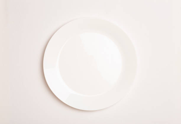 Empty white ceramic plate on white tablecloth background. Minimal concept stock photo