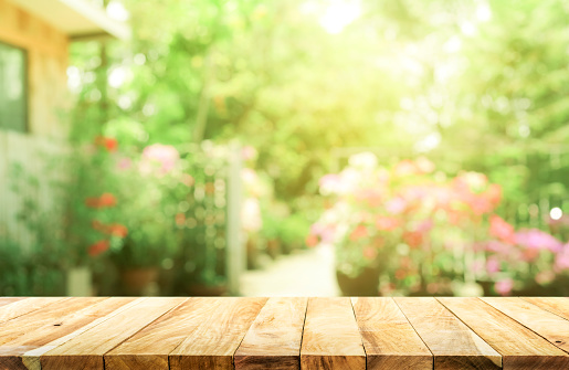 Empty wood table top on blur abstract green from garden and house background