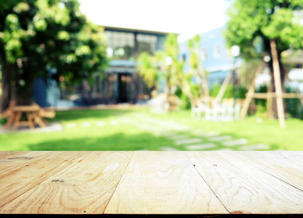 lege houten tafelblad op blur abstract groen van de tuin in de ochtend achtergrond. kan worden gebruikt voor het weergeven of monteren van uw producten - formele tuin stockfoto's en -beelden