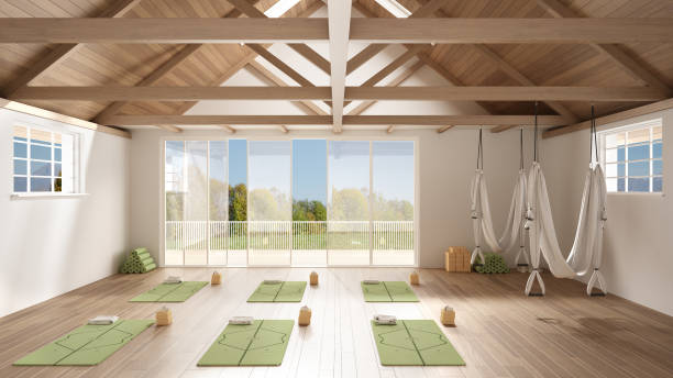 Empty yoga studio interior design, minimal open space with mats, hammocks and accessories, wooden floor and roof, ready for yoga practice, panoramic window with summer panorama stock photo