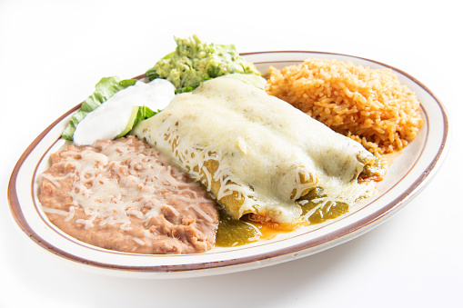 Two chicken enchiladas topped with delicious green sauce. Garnished with guacamole and sour cream on white background