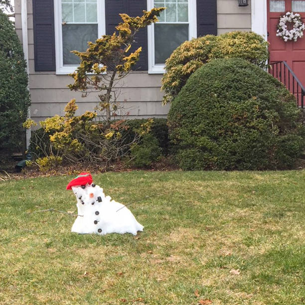 End of Winter little snowman remains End of Winter little snowman remains on suburban  lawn melting snow man stock pictures, royalty-free photos & images