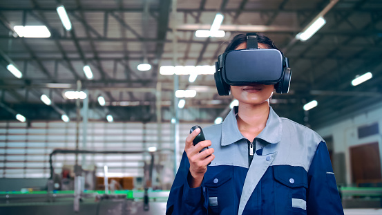 Engineer is using virtual reality glasses to inspect the factory's mechanical control system.