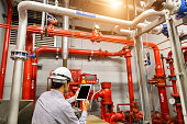istock Engineer with tablet check red generator pump for water sprinkler piping and fire alarm control system. 1097682848