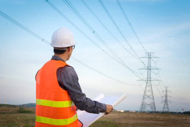 Engineering worker checking location site near to High voltage tower. Engineering worker checking location site near to High voltage tower. af_istocker stock pictures, royalty-free photos & images