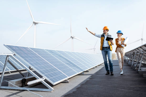 Engineers on a solar power plant View on the rooftop solar power plant with two engineers walking and examining photovoltaic panels. Concept of alternative energy and its service renewable energy stock pictures, royalty-free photos & images