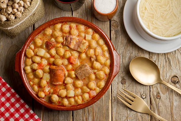 English Cocido Spanish Cocido in an earthenware pot and soup in a white bowl on a wooden table cooked stock pictures, royalty-free photos & images