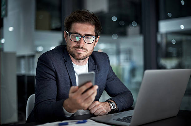 Enhancing his entrepreneurial ambition with the right tools Shot of a young businessman using his laptop and phone at work business finance and industry photos stock pictures, royalty-free photos & images