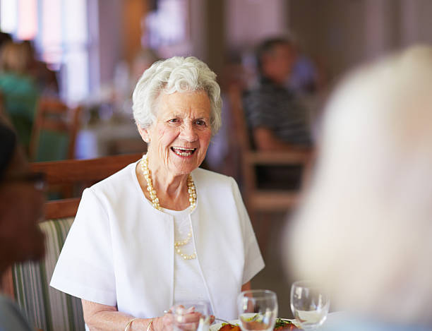 Cheerful old lady at lunch with her elderly friends at their old age...