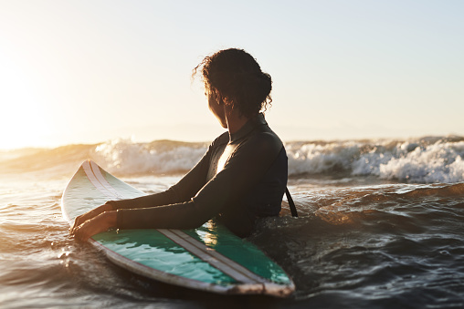 Shot of a beautiful young woman surfing in the ocean