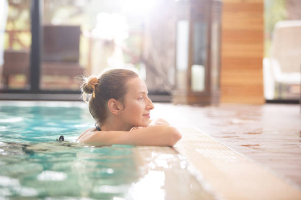 Enjoying peace and quiet Side view of a Caucasian woman resting at poolside. She is enjoying a quiet weekend at the spa. spa stock pictures, royalty-free photos & images